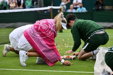 Glyn Kirk / AFP Britain's Katie Boulter (front) and Australia's Daria Saville help ball boys and girls to pick up orange confetti