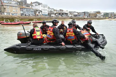 PA Media Police officers are seen on a rigid inflatable boat in St Ives in the sea