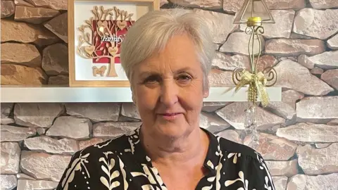 BBC Wendy Falconer standing in a living room. She is middle-aged, with short blonde hair.