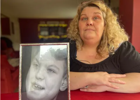 Jamie Niblock/BBC Nicky Brown with a photo of her son Tom