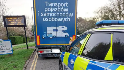 Cambridgeshire Constabulary A police car behind an AMBRO Logistics lorry.