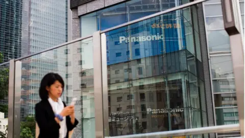 Getty Images A woman walks past a Panasonic building in Tokyo on May 11, 2017.
