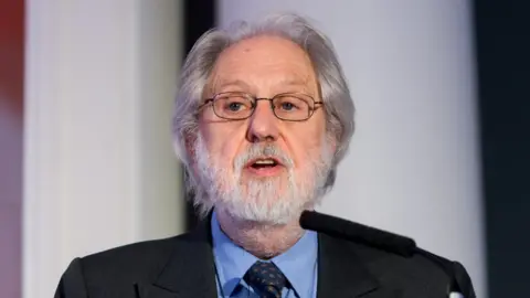 Getty Images Lord Puttnam is seen speaking from a podium