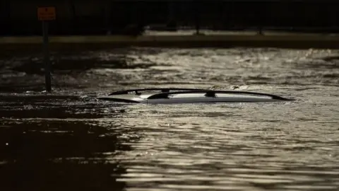 Getty Images The roof of a submerged car is pictured in a flooded street in Mytholmroyd, northern England