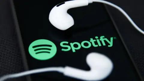 Getty Images Spotify logo with iPhone headphones