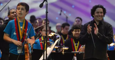 Getty Images Maestro Gustavo Dudamel applauds as he conducts the children from the Big Noise Orchestra during the Big Concert on 21 June 2012 in Stirling, Scotland