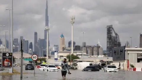 Reuters A man in floodwater in Dubai