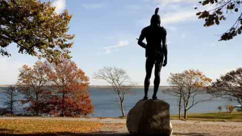 Getty Images A Wampanoags statue stands on a hill overlooking Plymouth Harbor in Massachusetts.