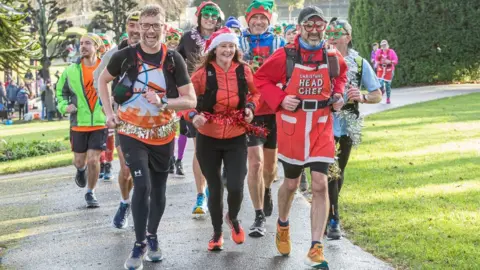 Dorsetbays Andy Mutter running with a group of supporters in Christmas-themed outfits