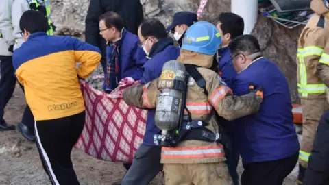 EPA A handout photo made available by Kyongnamdomin Ilbo shows South Korean firefighters carrying a victim after a fire at a hospital in Miryang, South Korea, 26 January 2018