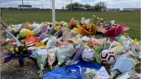 Flowers and football boots at the scene