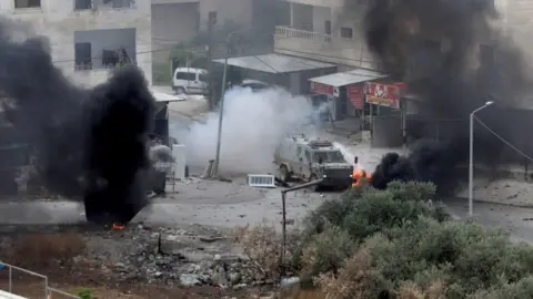 EPA An explosive charge detonates near an Israeli armoured vehicle during an Israeli military raid in the West Bank city of Jenin (19 June 2023)