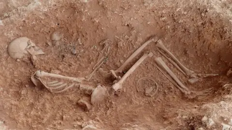 University of Sheffield Skeleton of a woman cradling a baby in her left arm buried in the ground