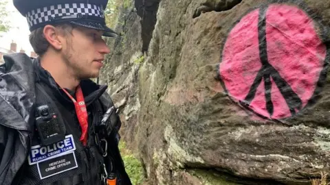 Historic England A heritage crime officer examines graffiti sprayed onto ancient remains in Chester, Cheshire