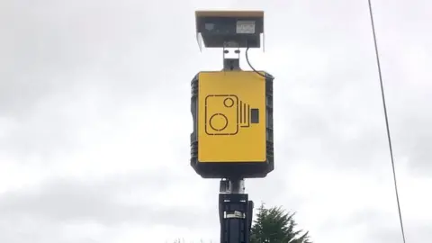 Bob Filmer An automatic number plate recognition camera on a pole against a cloudy sky