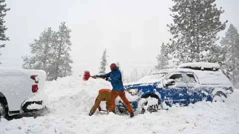 Getty Images A man shovels snow in the Sierra Nevada