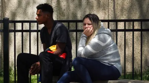 Getty Images Migrant families from Venezuela watch as their children play in a Chicago park, where a field house has been converted into a migrant shelter