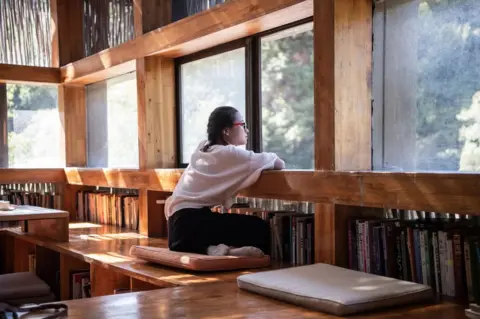 FRED DUFOUR/AFP/Getty Images A woman looking out of a window in Liyuan Library