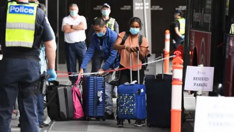 Getty Images Returning Australian passengers shepherded by police into hotel quarantine