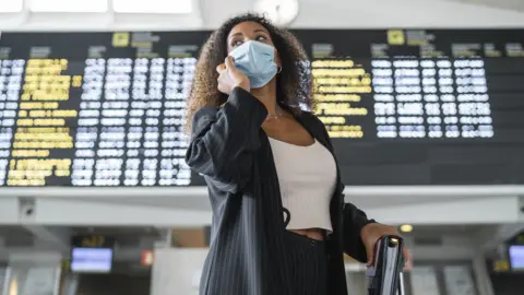 Getty Images Woman wearing face mask at an airport