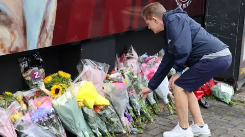 Sharon Burns laying flowers at Shankill Road mural