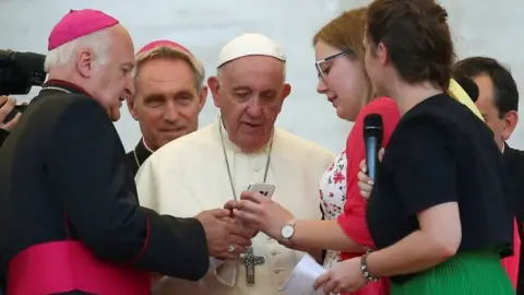 Reuters A priest shows Pope Francis a phone