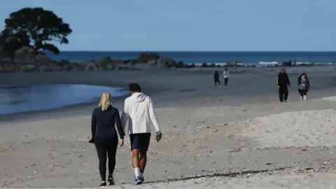 Getty Images People walking on a beach in New Zealand