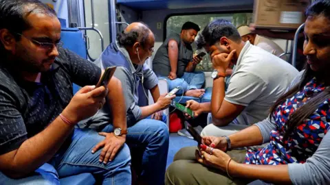 Getty Images Indian train passengers checking their phones