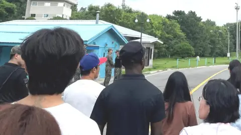 Reuters Travis King (wearing black shirt and black cap) on the border between the two Koreas, 18 July 2023