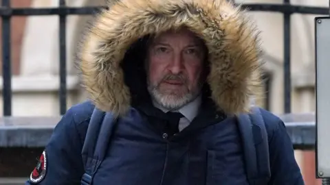 PA Media Michael Lousada wearing a furry hood and leaving the Royal Courts of Justice in London