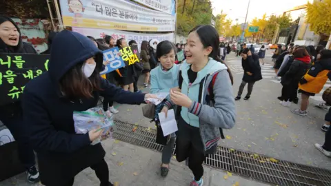 Getty Images Younger students chanting and handing out sweets as a symbol of good luck