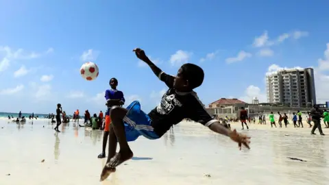Reuters Boy playing football on the beach