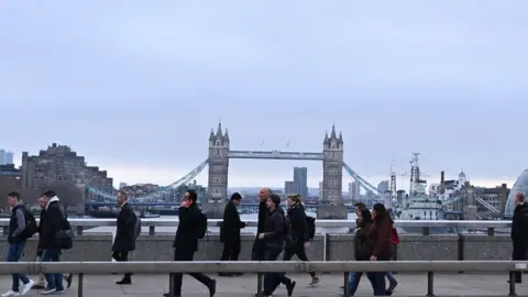 Getty Images Commuters on a bridge over the River Thames in London