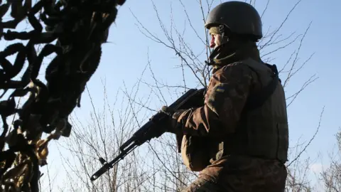 A Ukrainian serviceman keeps watch at a position on the frontline with Russia-backed separatists not far from Gorlivka, Donetsk region