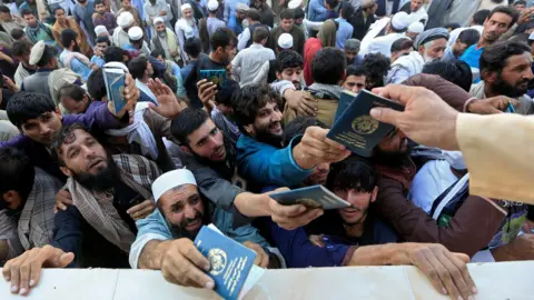 Reuters A crowd of men holding up their passports