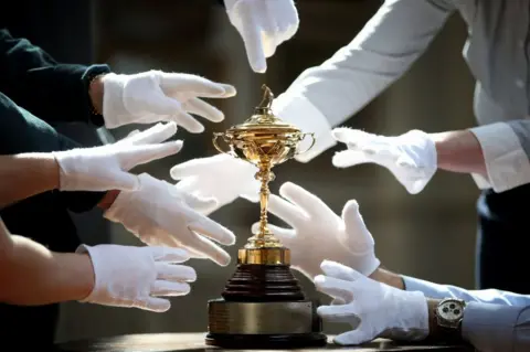 Jane Barlow/PA Auction house staff at Bonhams in Edinburgh, try to get their hands on a replica Ryder Cup.