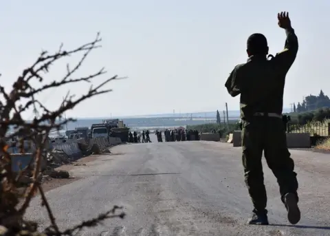 Getty Images A fighter from the Kurdish People's Protection Units (YPG) gestures at displaced Syrians walking towards a Kurdish controlled checkpoint between the rebel-held town of Azaz in northern Syria and the city of Afrin, along Syria's northern border with Turkey, as they attempt to cross in June 2017