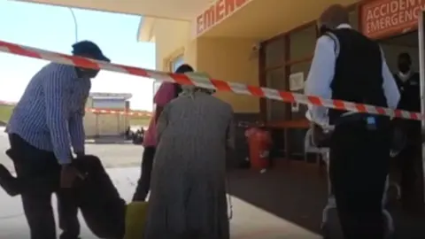 BBC A patient being carried into an emergency entrance at Dora Nginza hospital in the Eastern Cape, South Africa