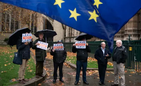 Getty Images Pro-Brexit campaigners hold posters beneath an EU flag flown by Remain demonstrators outside Parliament on 3 December
