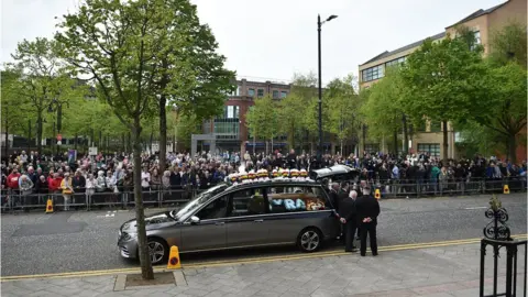 Getty Images The funeral hearse arrives outside St. Anne's Cathedral in front of crowds of mourners.