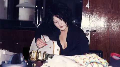 PA Media A photograph of actress Drew Barrymore playing the guitar