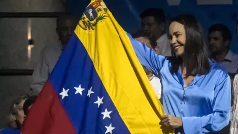 Maria Corina Machado (C) holds the Venezuelan flag as she celebrates the primary election results in Caracas, Venezuela, early 23 October 2023.
