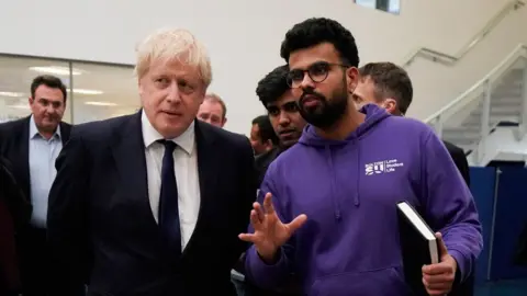Getty Images Prime Minister Boris Johnson speaks to a student during a visit to Bolton University chancellors building after a huge blaze