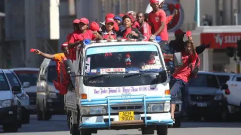 EPA MDC supporters dressed in red hang from a vehicle during a protest in Harare, Zimbabwe - Wednesday 11 July 2018