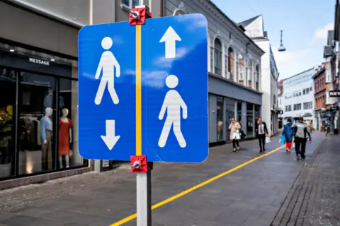 Reuters A yellow stripe is painted in the middle of a pedestrian street to help people comply with the social distance guidelines