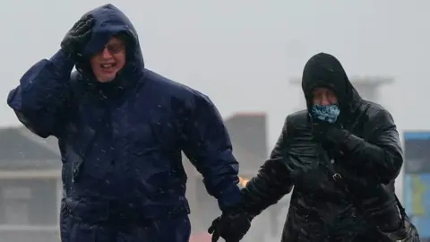 PA Media People brave the weather as they make their way along the sea front in Southsea as Storm Barra hit the UK and Ireland with disruptive winds, heavy rain and snow on Tuesday.