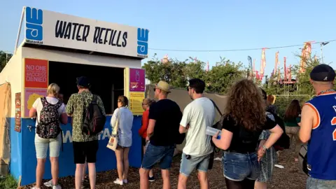 Festival-goers queue for water