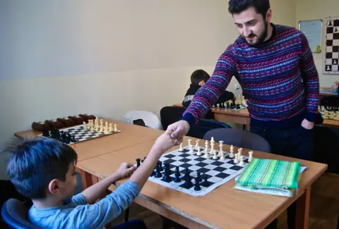A teacher congratulates a young opponent