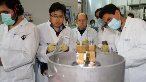 AFP File photo showing IAEA inspectors and Iranian technicians disconnecting connections between centrifuge cascades at the Natanz uranium enrichment facility in Iran (20 January 2014)