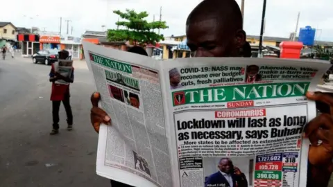 Getty Images Man reading newspaper in Lagos street